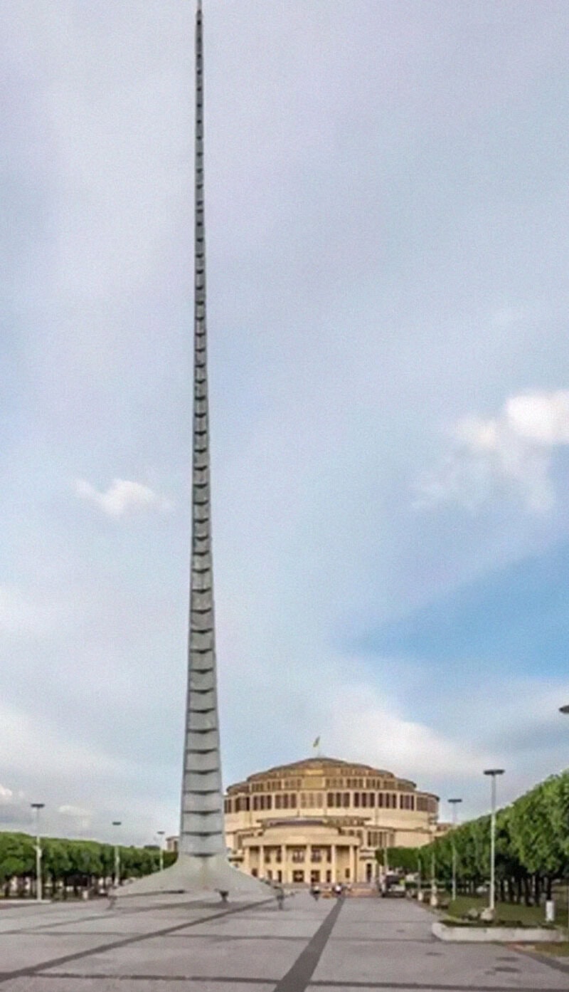 Tall, slender tower with a spiral pattern extending into a cloudy sky.