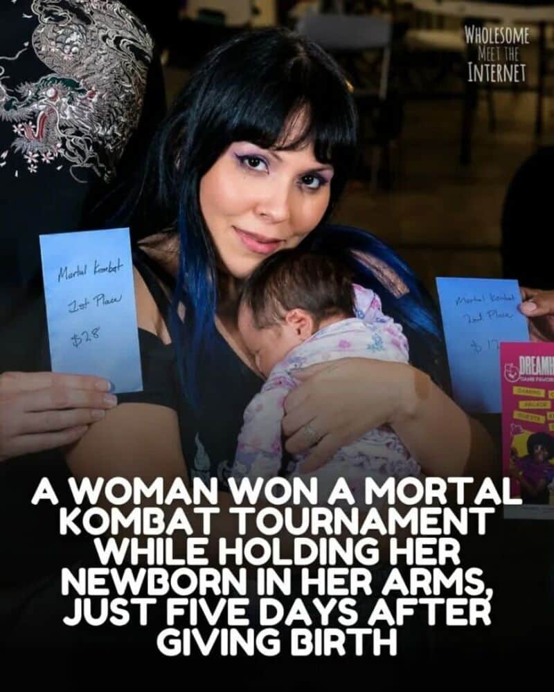 Woman holding newborn after winning Mortal Kombat tournament, smiling at camera.