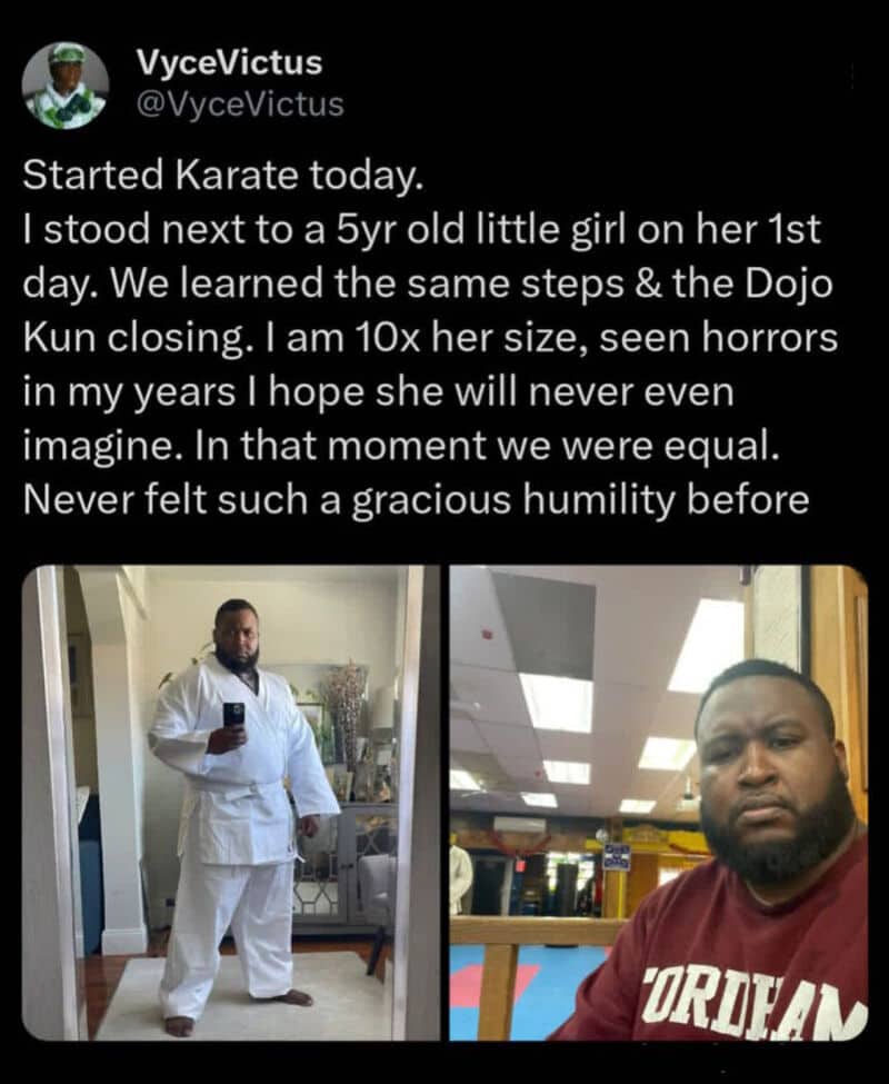 Man in white karate gi standing in mirror, man in maroon shirt sitting in dojo.