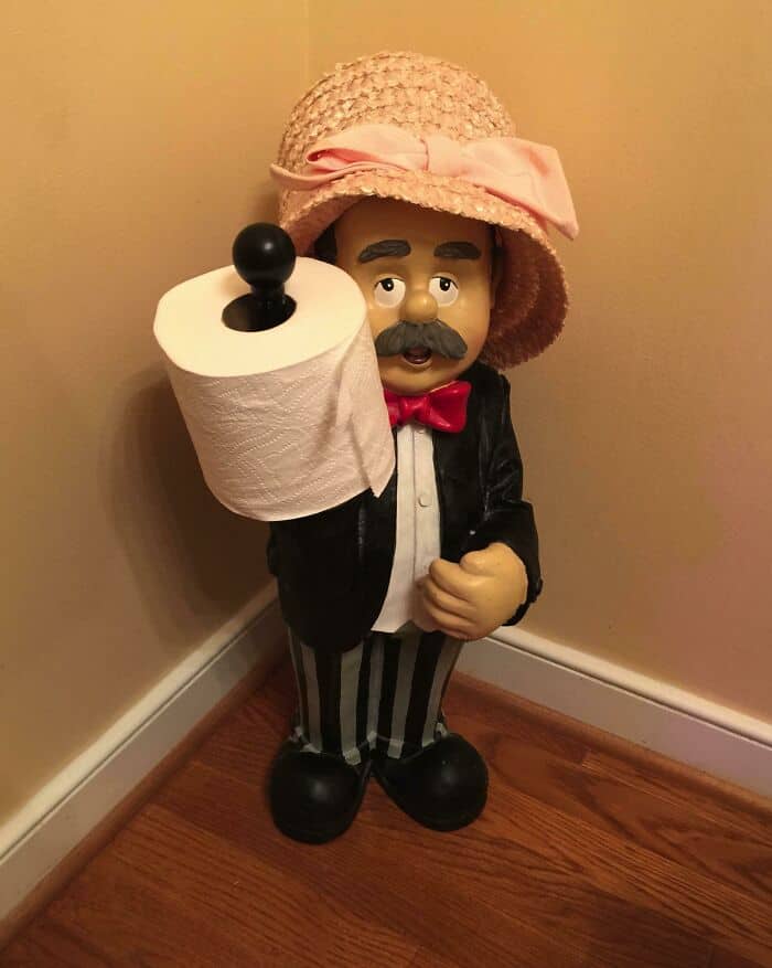 Vintage-style figurine of a man with a mustache holding a toilet paper roll.