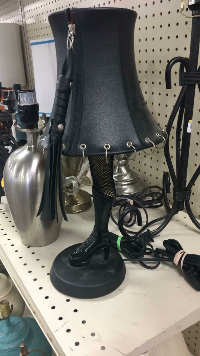 LED lamp shaped like a black high-heeled boot with a lampshade, on a store shelf.