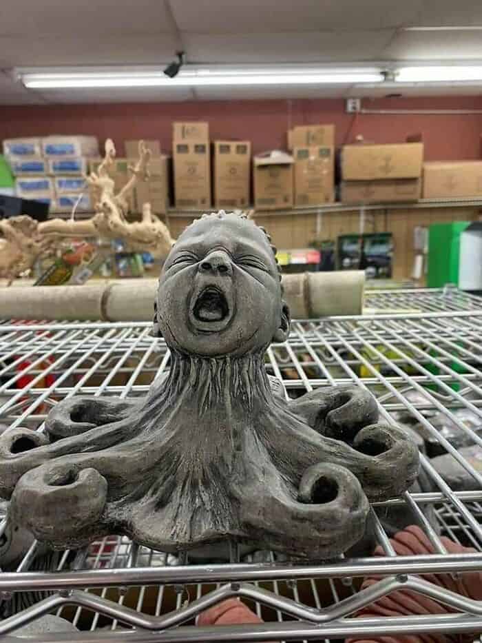 Artistic sculpture of a child's face with an octopus body on a wire shelf.