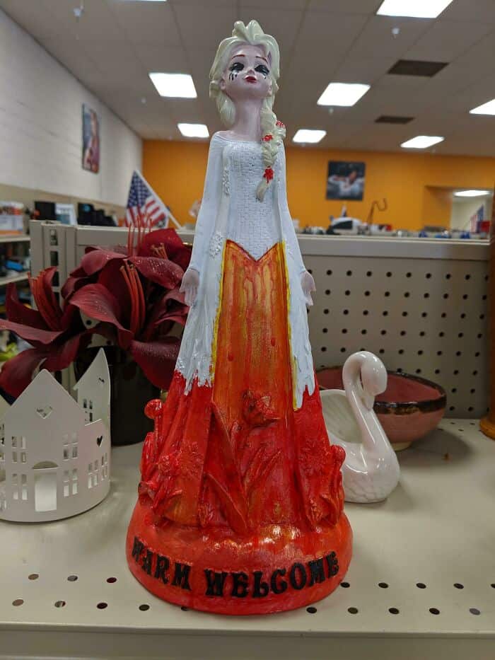Warm Welcome figurine with a white dress and orange skirt, displayed on a store shelf.