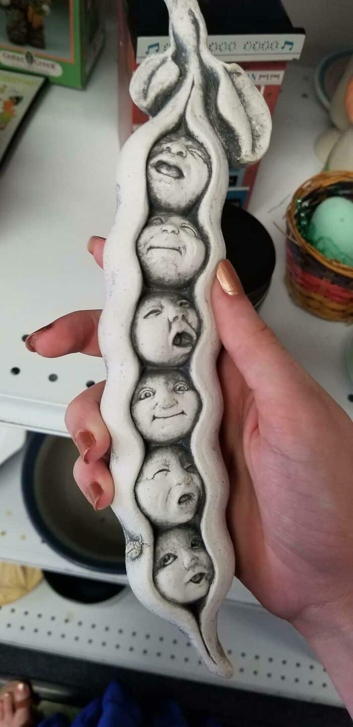 Hand holding a decorative object with multiple faces carved into it, displayed in a store.