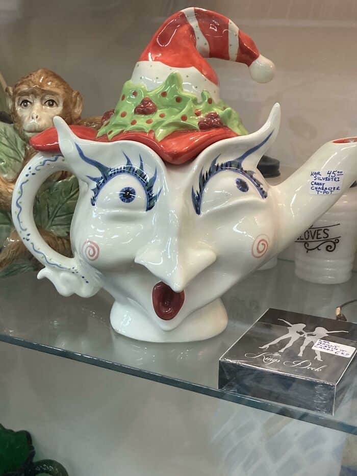 Whimsical ceramic teapot with a face, Santa hat, and holiday decorations.