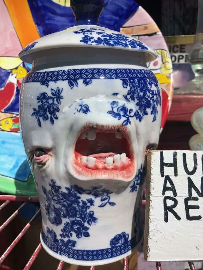 Unique ceramic container with a face and open mouth, decorated with blue floral patterns.