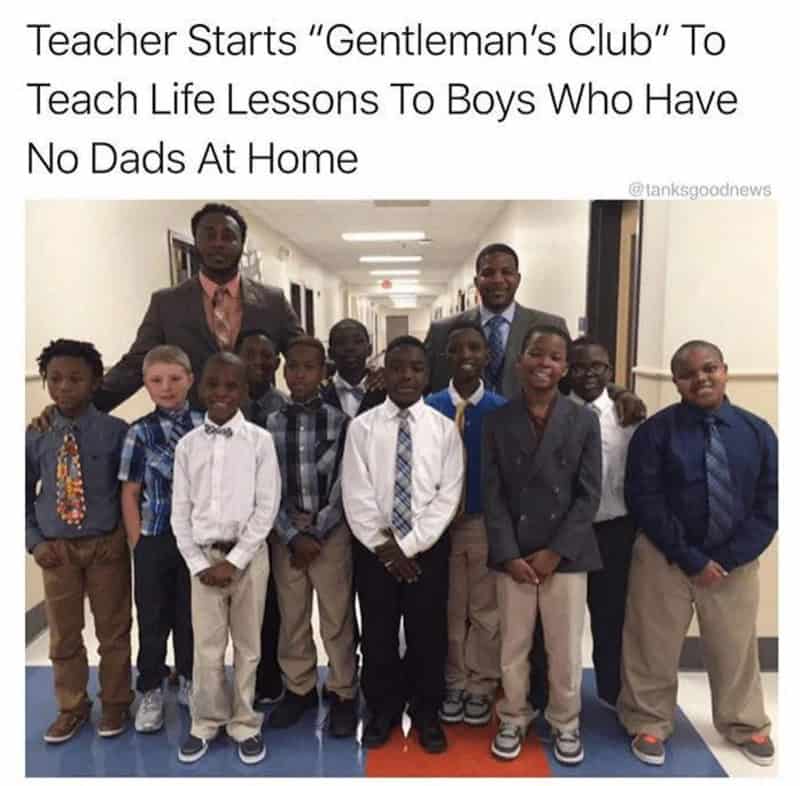 Group of boys and two men in a school hallway, dressed in formal attire.