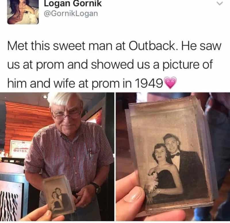 Man holding a vintage photo of himself and a woman at prom in 1949.