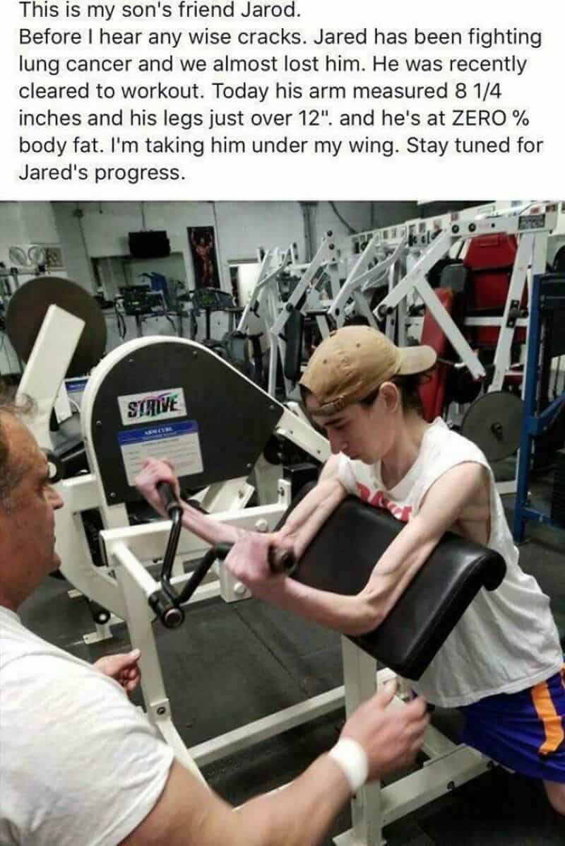 Young boy lifting weights with assistance in gym, smiling.