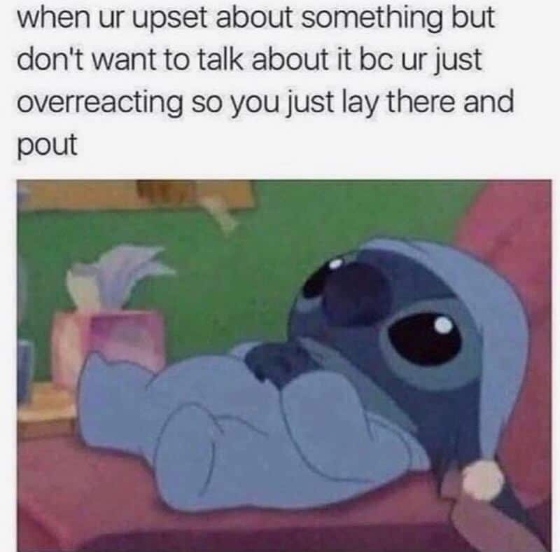 A cute cartoon puppy lying on its back with big eyes, looking sad and resting on a pink cushion.