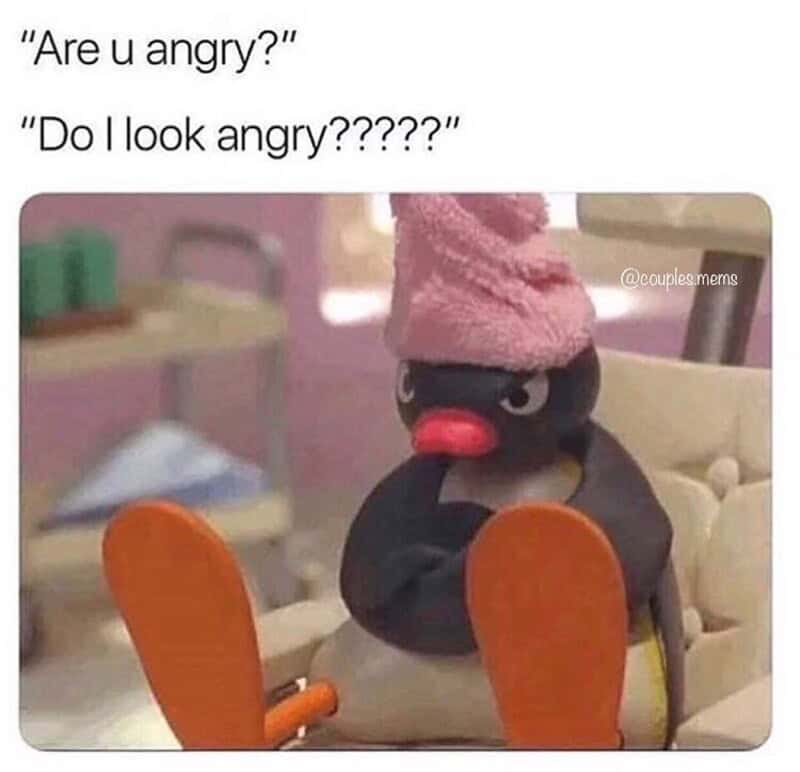 Cute angry plush toy with pink hat and orange feet, sitting on a chair.