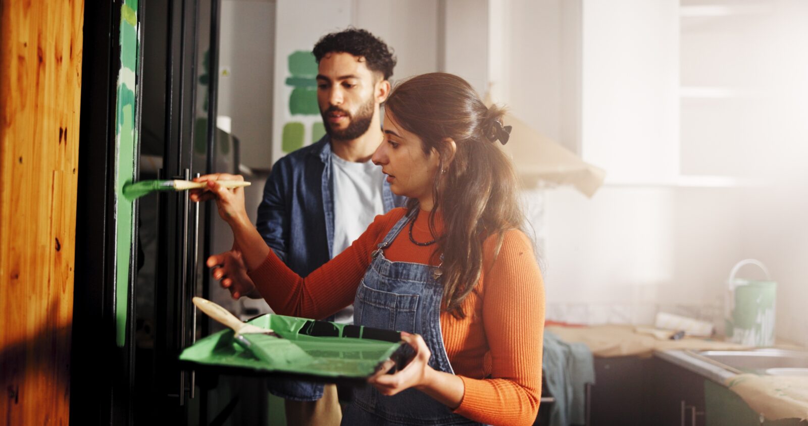 Painting a wall with a man and woman in a kitchen.