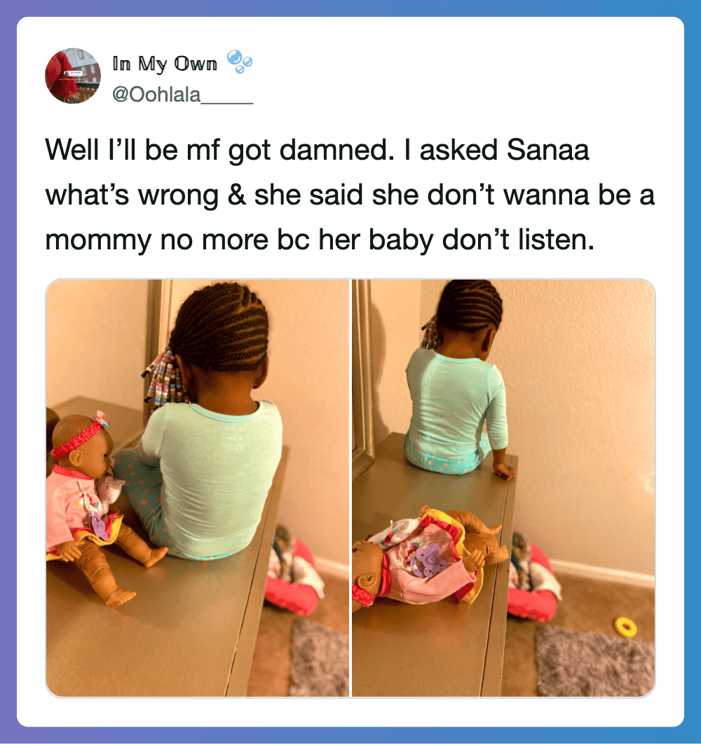 Child sitting on table with doll, facing away, in a room.