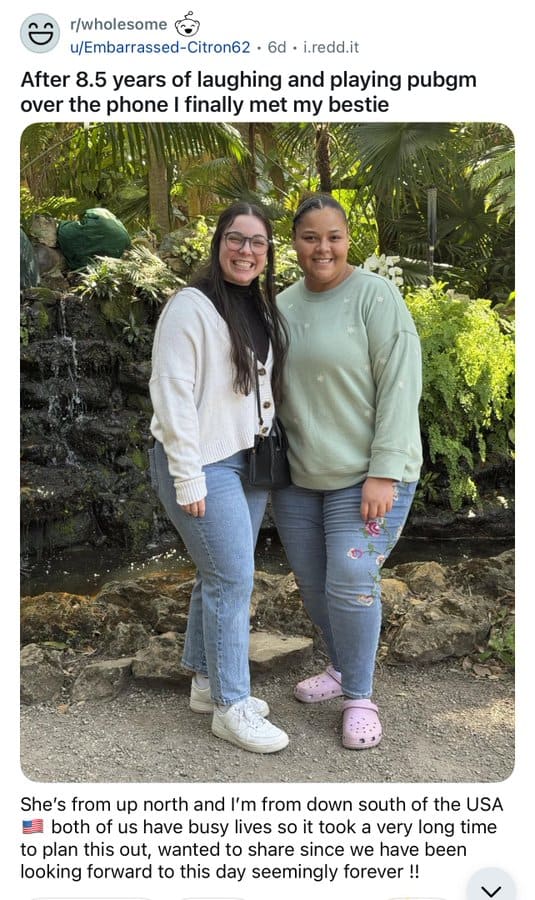 Two women smiling outdoors, one in a white jacket and the other in a green sweatshirt.