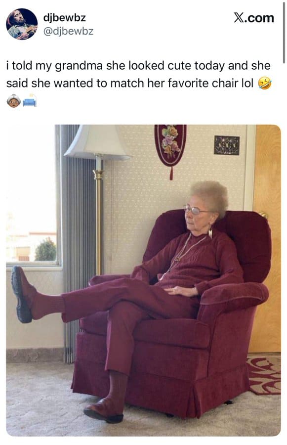 Elderly woman sitting in a red armchair, matching her favorite chair, with a window and lamp nearby.
