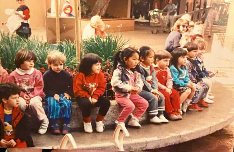 Children sitting on a circular bench at the mall in the 90s or 2000s.