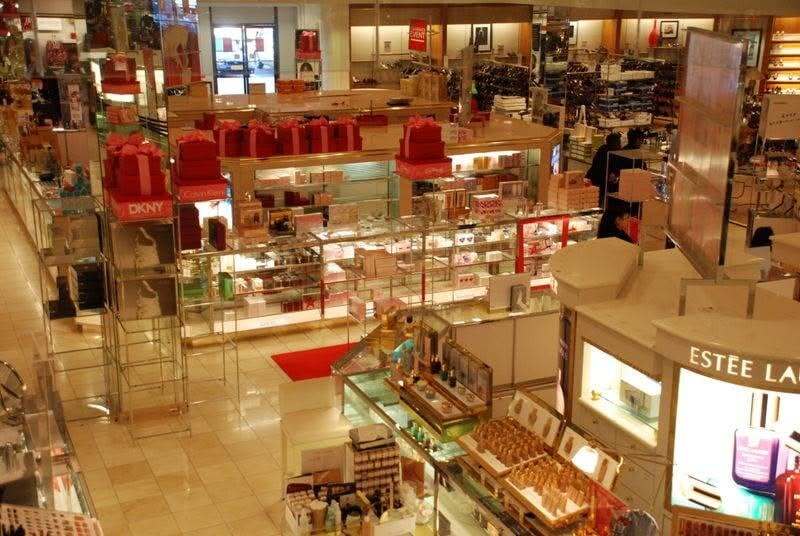 Inside a busy mall with various stores and displays, including cosmetics and accessories.