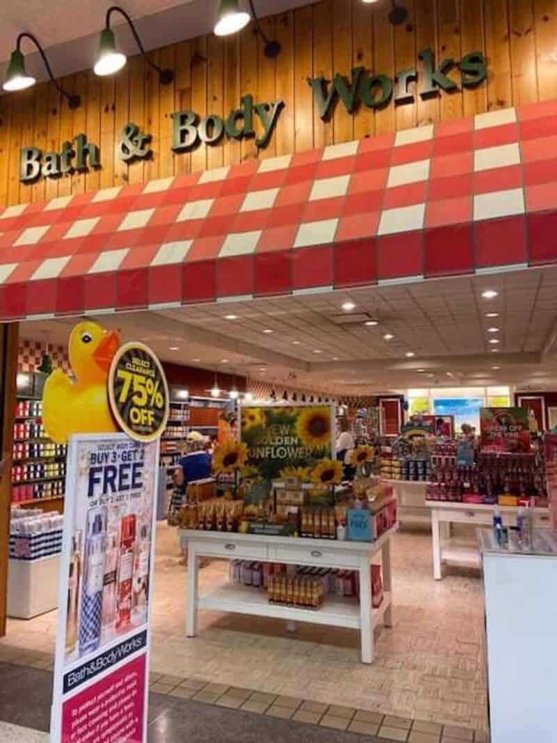 Bath & Body Works store entrance with red checkered awning and promotional signs.