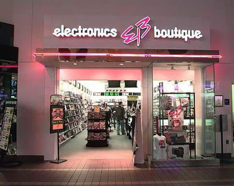 Electronics boutique store entrance with pink neon sign and glass display cases.