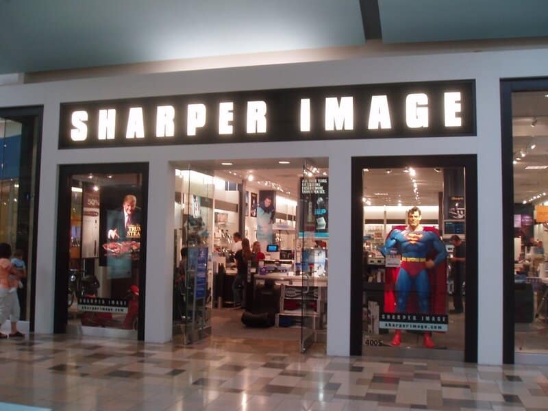 Sharper Image store in a mall with Superman figure display outside.