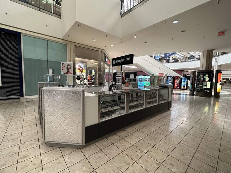 Empty mall kiosk with sunglasses and accessories, no customers present.