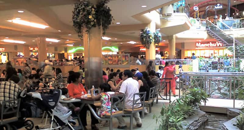 People dining at tables in a mall food court.