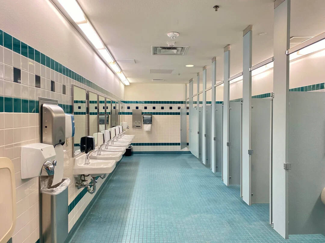 Empty public restroom with sinks and stalls, clean and well-lit.