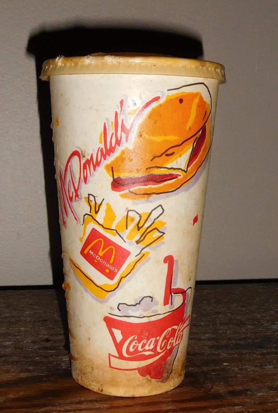 Vintage McDonald's cup with burger, fries, Coca-Cola logo, and straw.