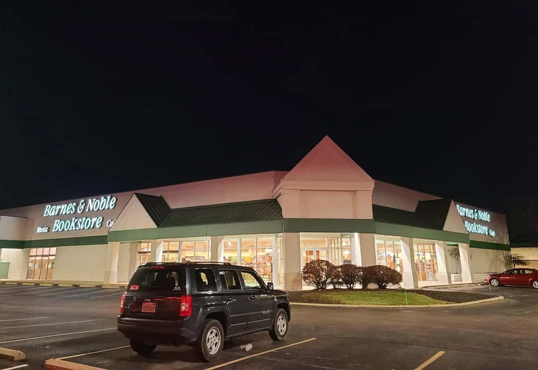 Barnes & Noble bookstore at night with parking lot and cars.