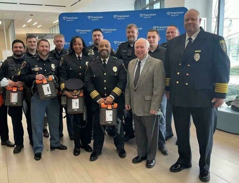 Group of police officers and officials at an event, some holding awards, in front of a blue backdrop.