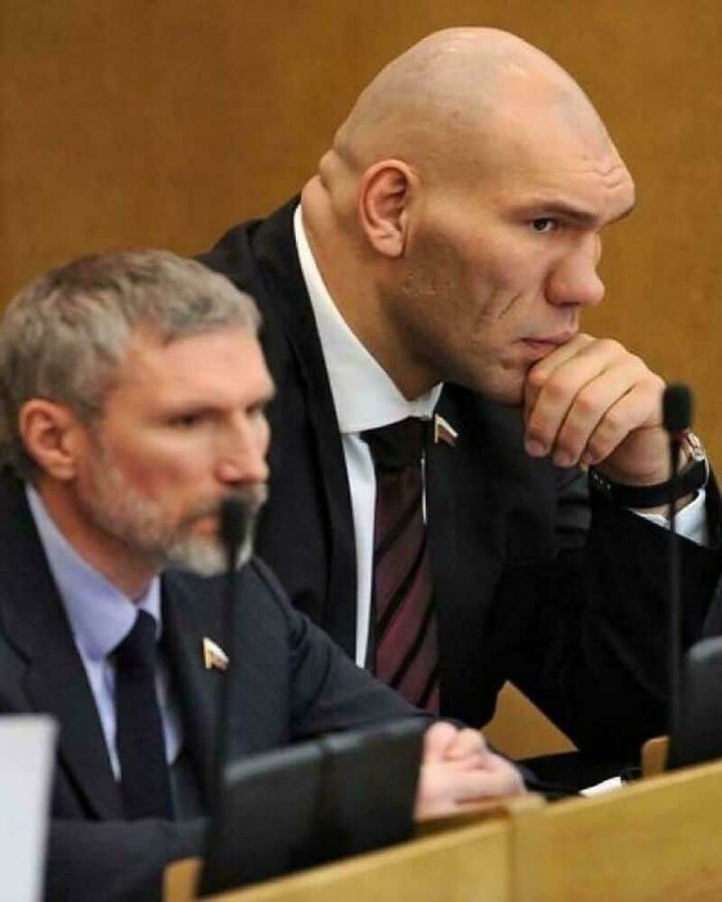 Serious men in suits at a formal meeting or hearing.