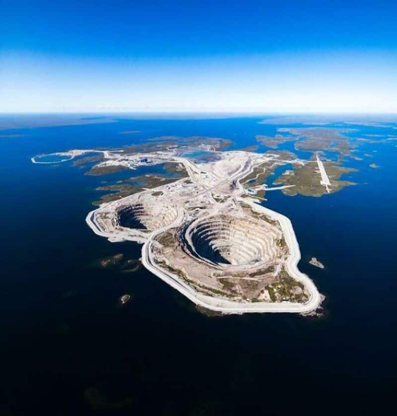 Aerial view of a large open-pit mine surrounded by water and land.