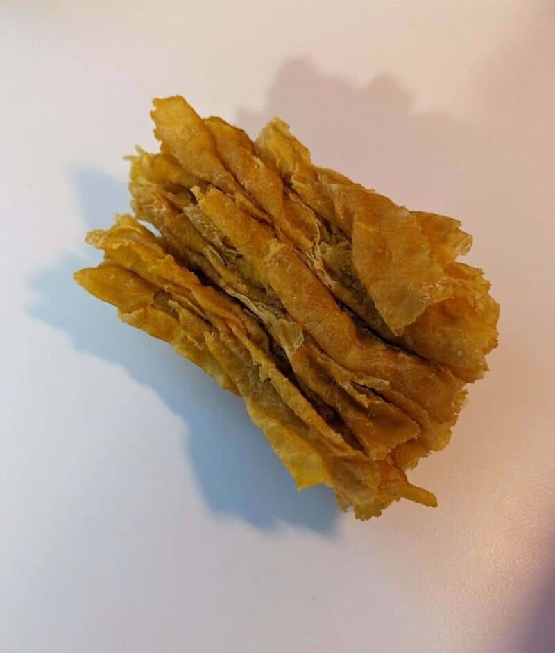 Stack of fried plantain chips on a white surface.