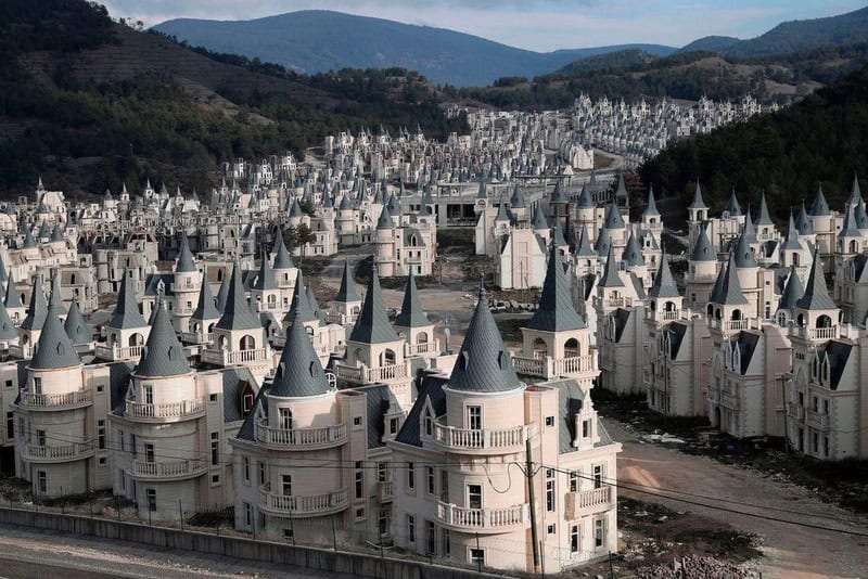 A large number of white castle-like buildings with pointed roofs in a hilly area.