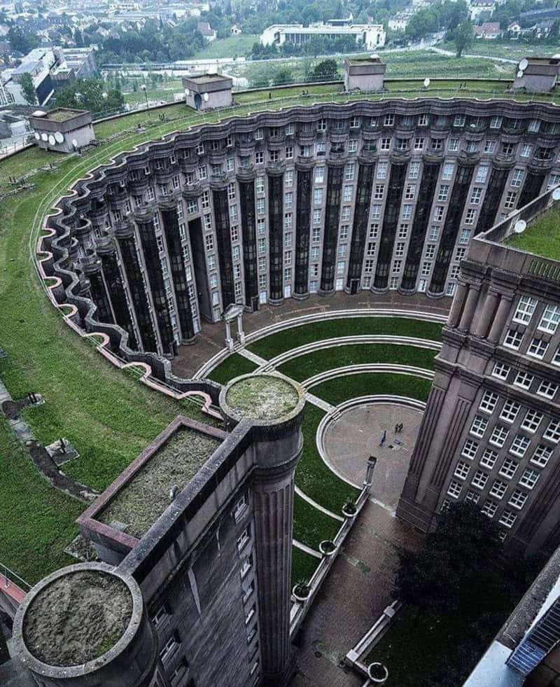 A large, circular building with a curved facade and multiple windows, surrounded by green grass and.