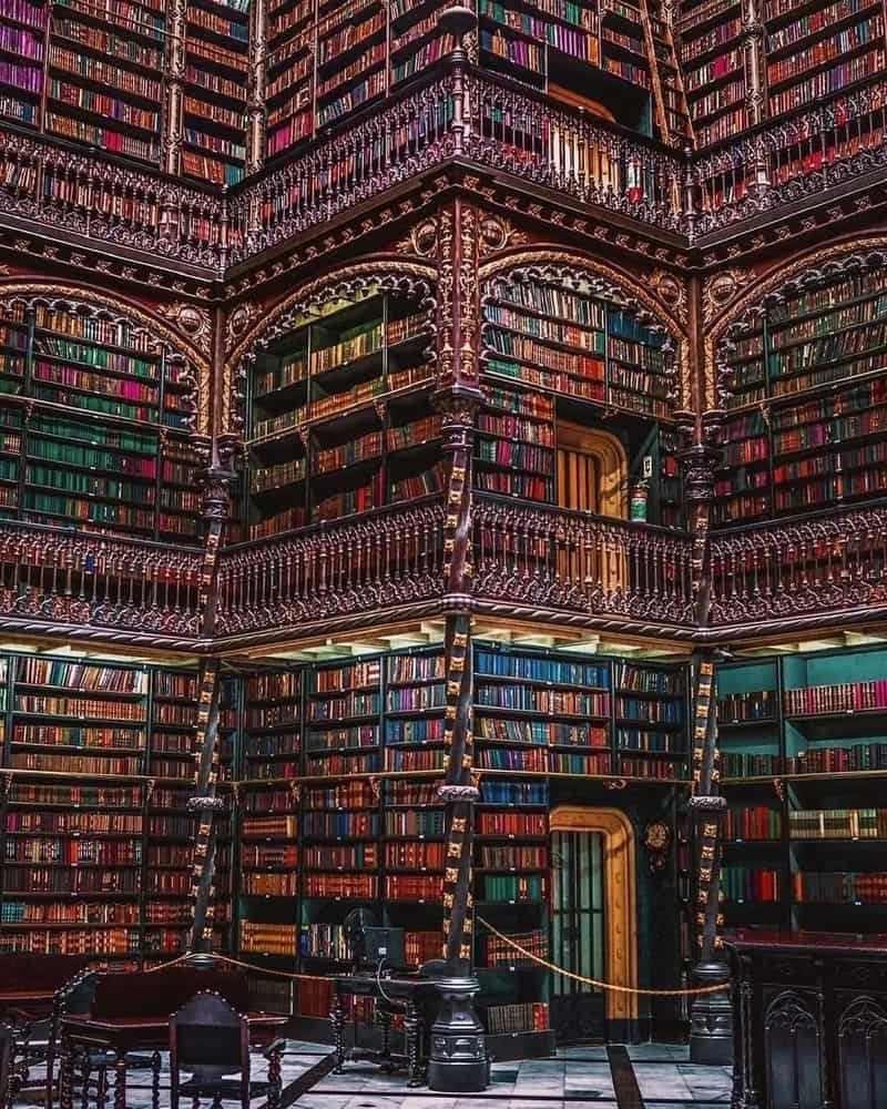 Interior of a grand, multi-level library with ornate ironwork and shelves filled with books.