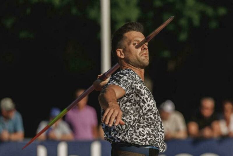 Man throwing javelin with a full crowd in the background.
