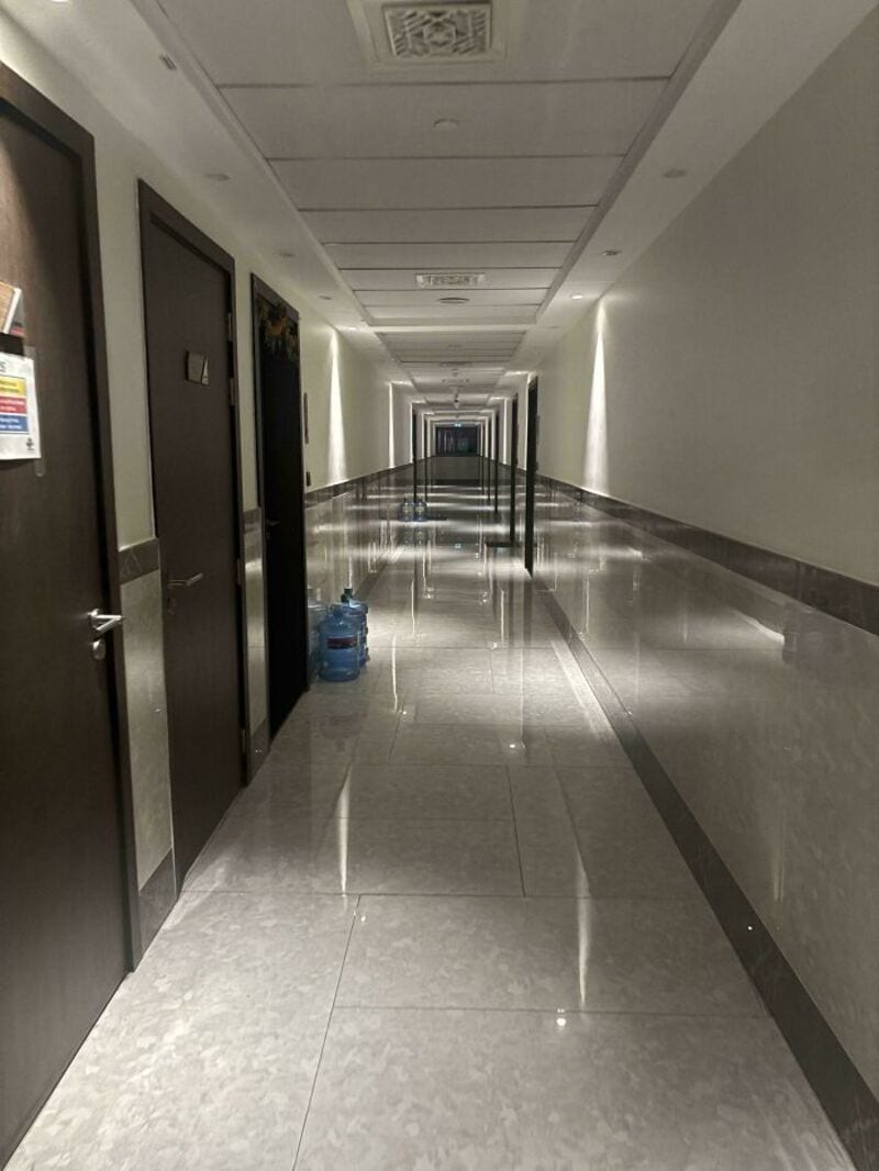 Long, empty hotel corridor with doors and a water bottle on the floor.
