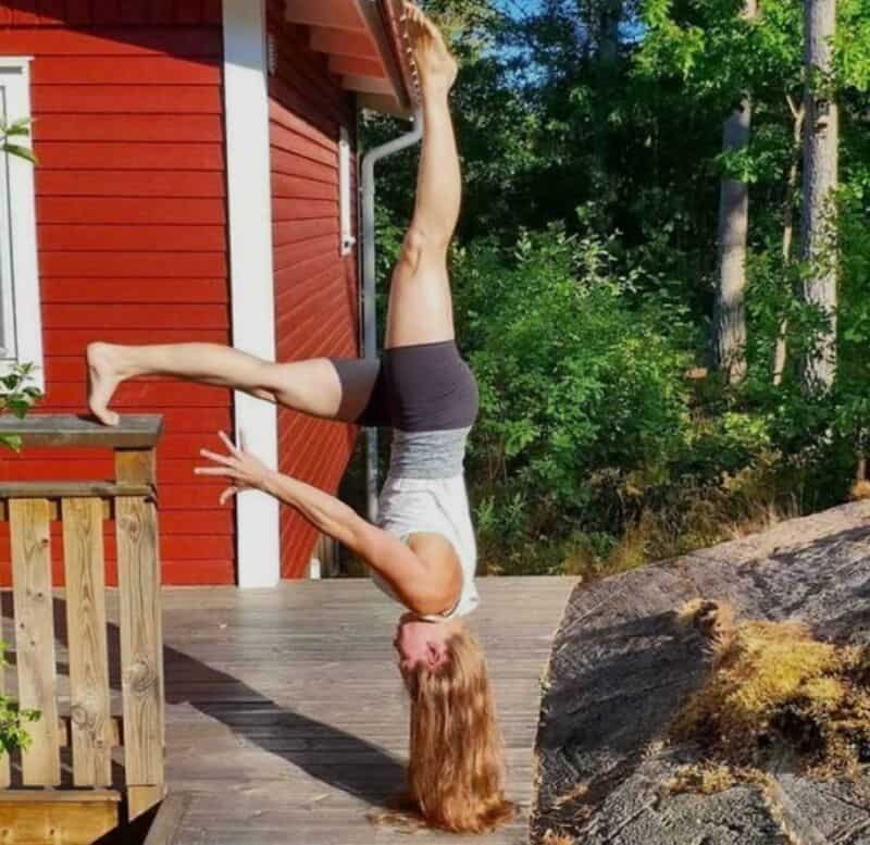 Woman doing a handstand with her legs against a wall outside.