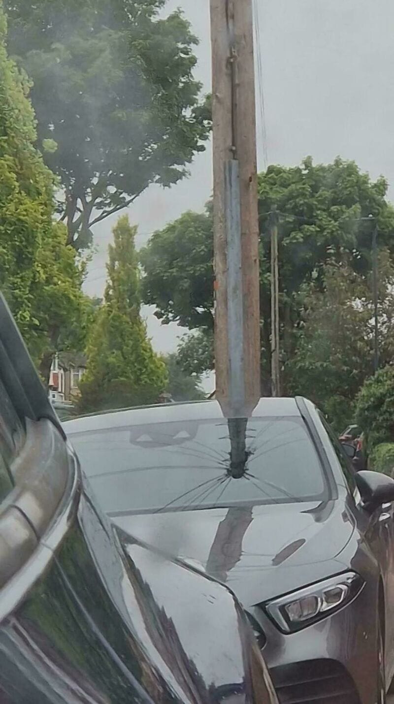 Car with a pole through its windshield creating a confusing perspective.