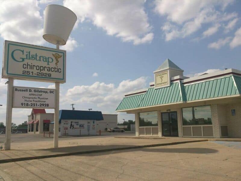 Chiropractic office with Gilstrap Chiropractic sign and a building with a green roof.