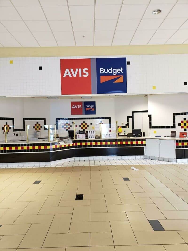 Avis and Budget signs at a car rental counter in an airport.