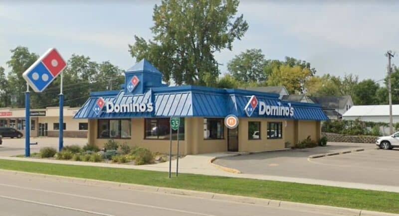 Domino's pizza restaurant with blue roof and signage, located on a street corner.