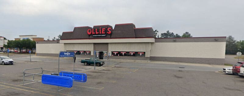 Ollie's store in a large parking lot with shopping carts and cars.