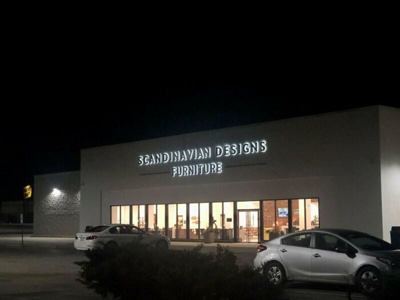 Scandinavian Designs Furniture store at night with cars parked outside.
