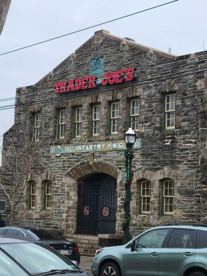 Trader Joe's store in a stone building with a sign and a lamp post outside.