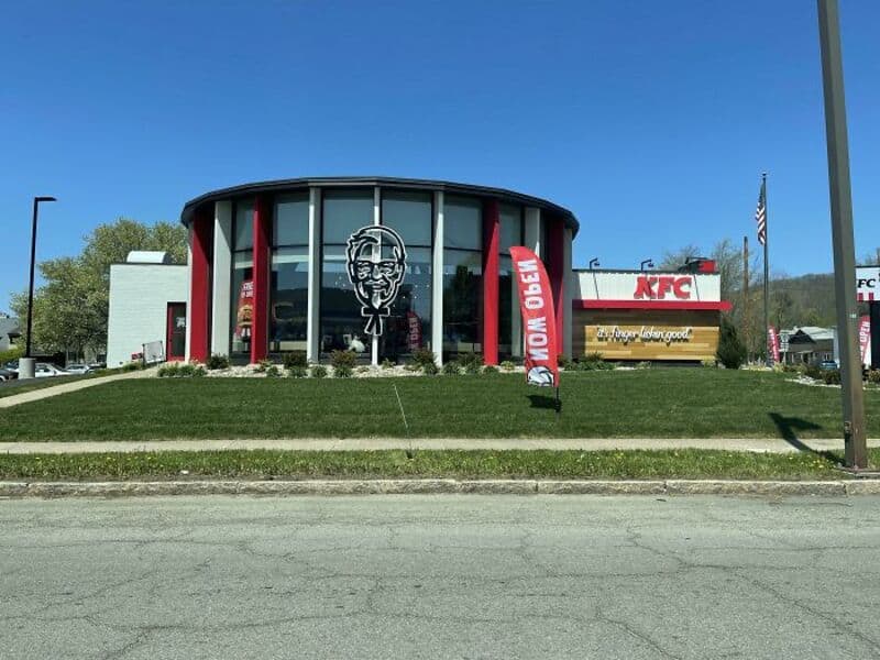 KFC restaurant with a large Colonel Sanders logo and flags outside.