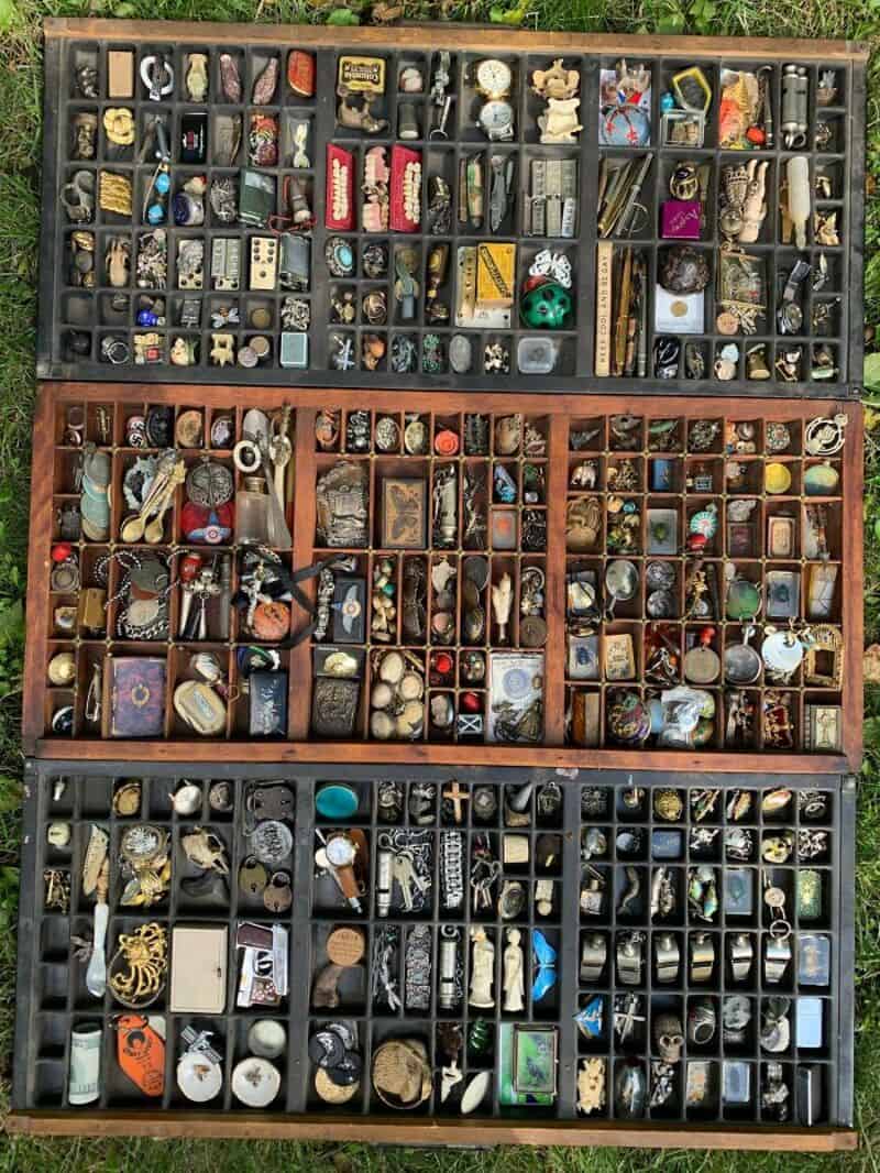Collection of various small objects and trinkets in a wooden box with compartments.