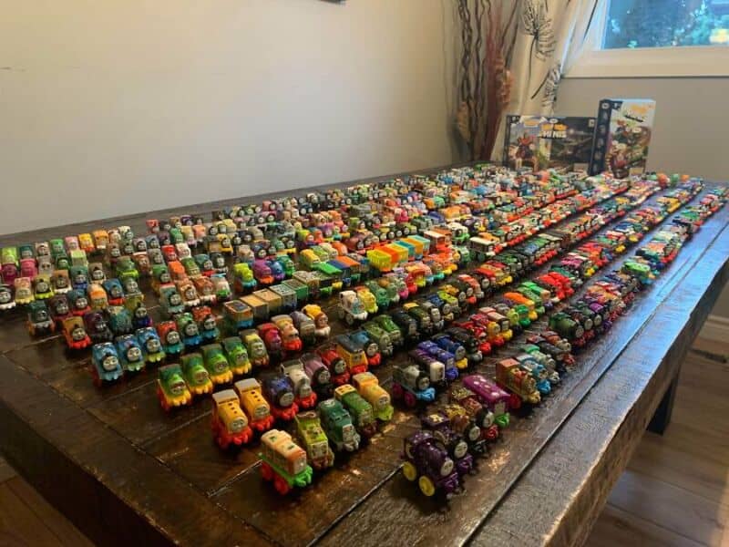 Collection of numerous small toy trains on a wooden table.