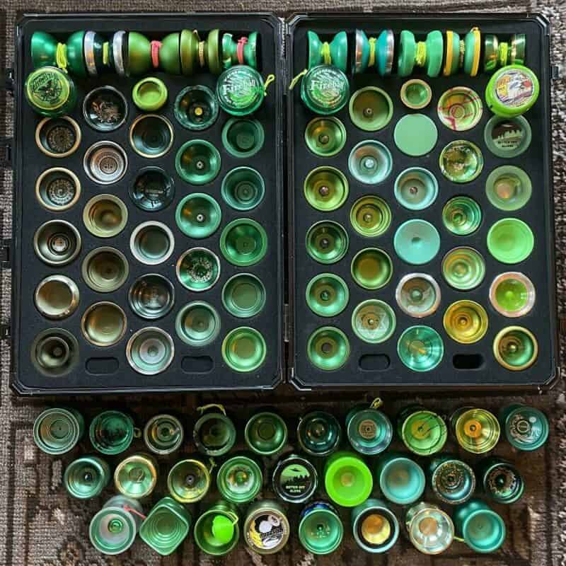 Collection of green yo-yos in a case and on a surface.